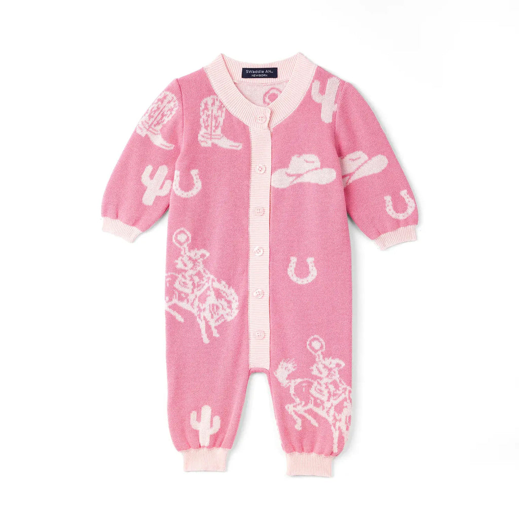 A pink long-sleeve baby romper with a white knit western-themed pattern featuring boots, hats, horseshoes, and cacti, shown flat on a white background. AdoraBaby.co.uk