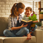 A woman and a young girl sit on a beige couch in a warmly lit living room, reading a book together. The girl holds a green plush cactus toy with a pink flower.