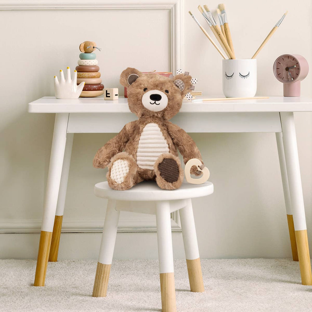 Teddy bear on a small white stool with a white table in the background