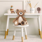 Teddy bear on a small white stool with a white table in the background