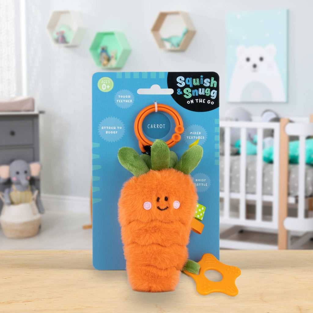 Carrot-shaped plush toy with a teether on a 'Squish & Snug' branded card in a nursery setting.