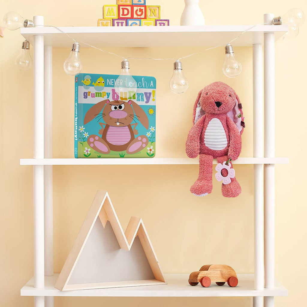 White shelving unit with children's toys and books against a yellow wall.