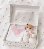 Adorababy.co.uk baby gift set in a white box with a clear window, containing a white and pink knit baby sweater, cream knit booties