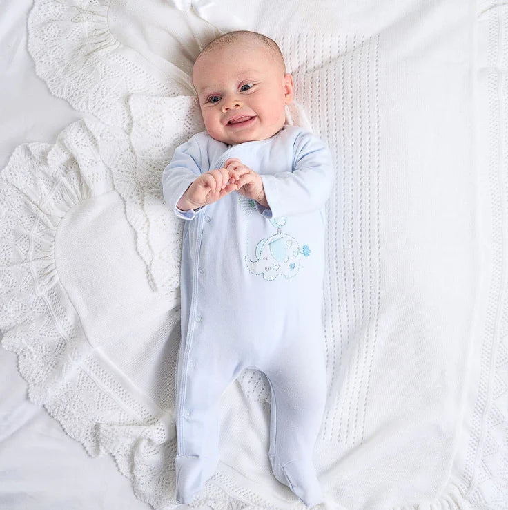 Baby in a light blue onesie with a design on a white textured blanket