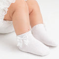 White baby socks with bows worn by a child on a light background adorababyco.uk