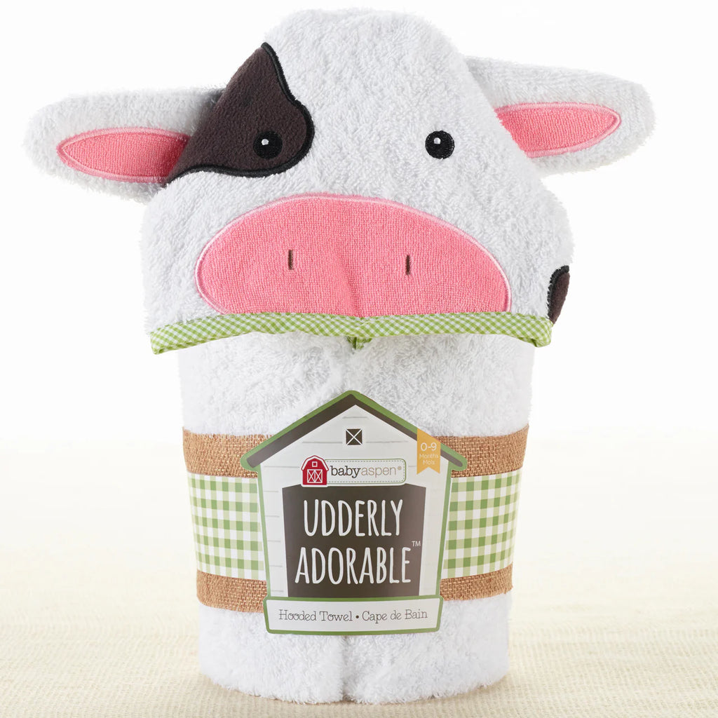 White Cow-shaped hooded towel with pink face and black ears, featuring a label on a white background.