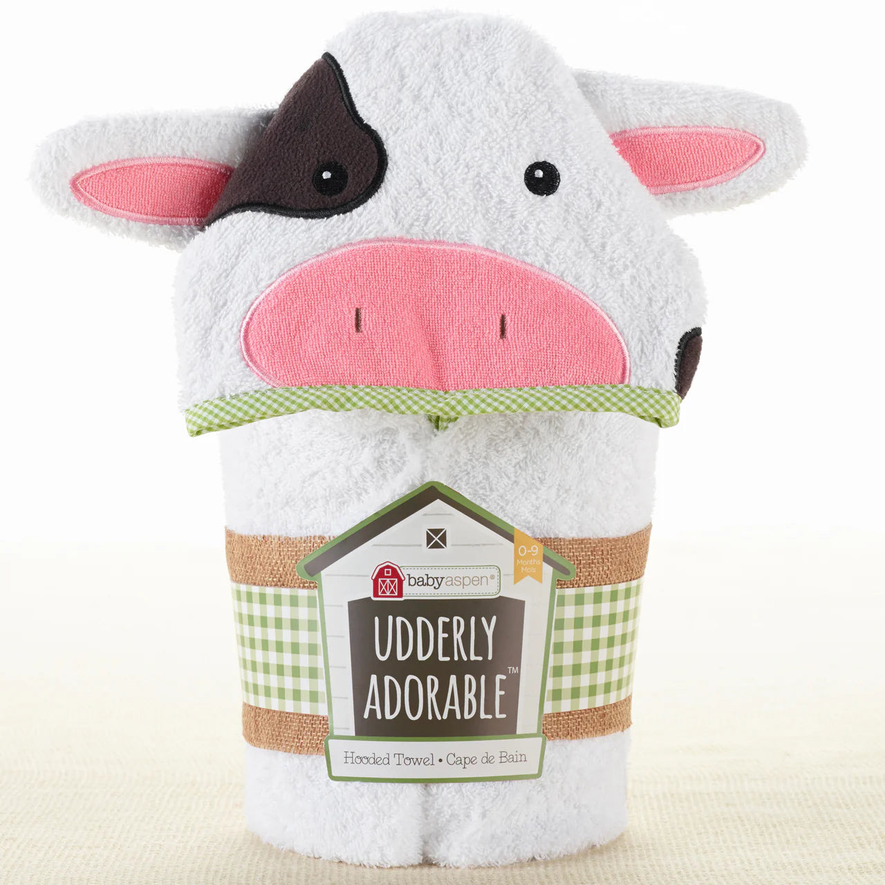 White Cow-shaped hooded towel with pink face and black ears, featuring a label on a white background.