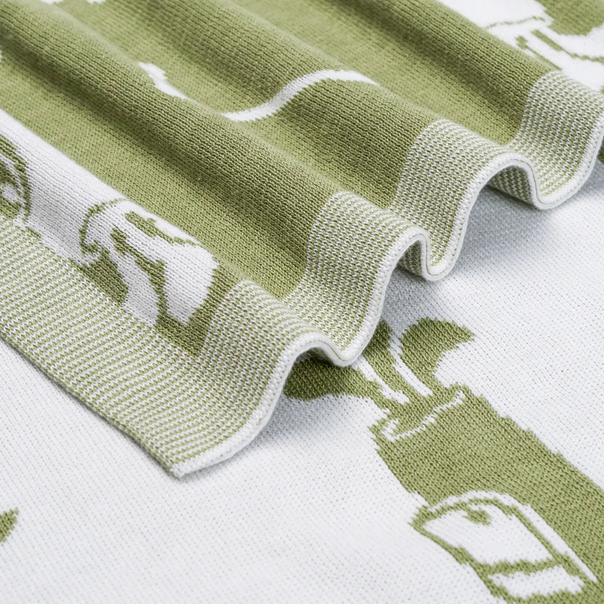 Close-up of a green and white patterned baby blanket with golf embroidery