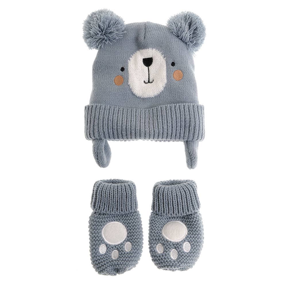 A baby winter hat and bootie set in dusty blue-gray. The knit hat features a bear face with a white snout, black nose, orange cheeks, and fluffy pom-poms on top.