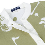Close-up of a knit polo shirt by Swaddle AN. featuring an olive green and white golf-themed pattern with a white ribbed collar and button placket.