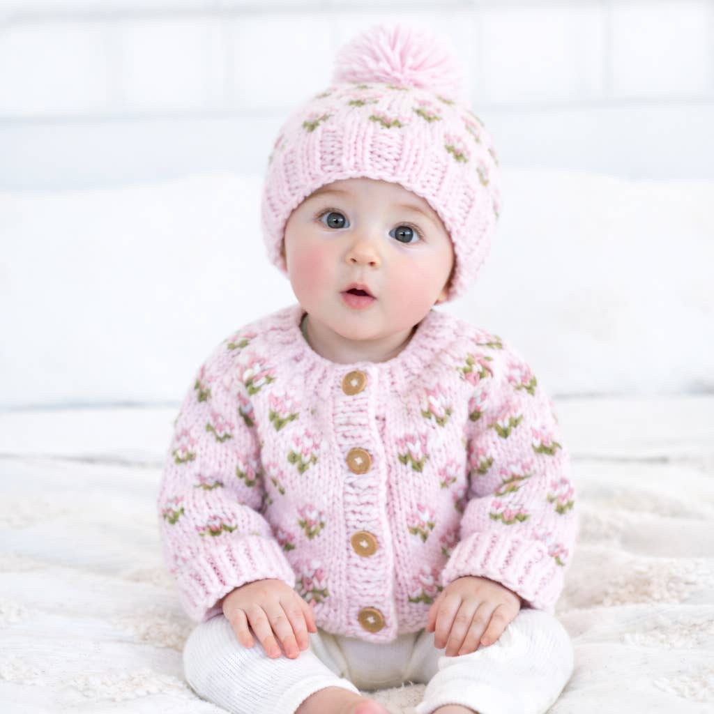 Baby wearing a Huggalugs hand knit pink knitted cardigan and hat on a white background - Adorababy.co.uk