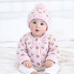 Baby wearing a Huggalugs hand knit pink knitted cardigan and hat on a white background - Adorababy.co.uk
