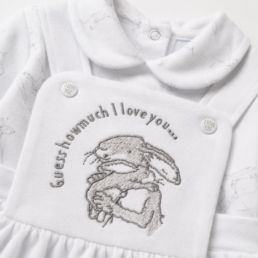 White baby outfit with embroidered design and text on a white background