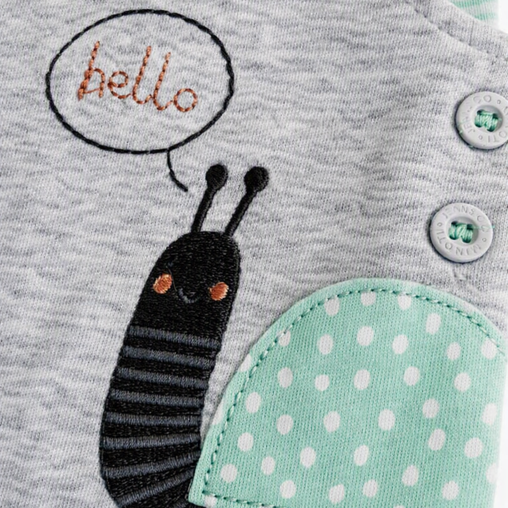 Close-up of a baby garment with a cartoon snail applique on a heather gray fabric. The snail has a black striped body, a mint green polka-dot shell, and a speech bubble that says "hello" in orange.