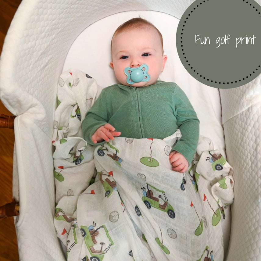 Baby in a crib with a green outfit and blue pacifier, surrounded by a golf-themed blanket.
