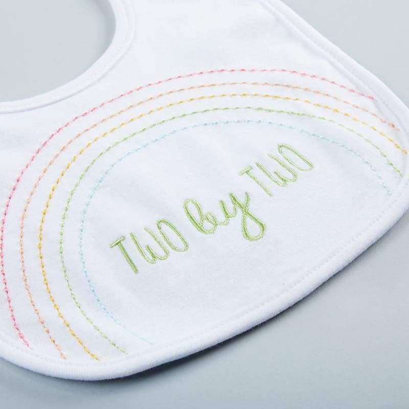 White bib with rainbow-stitched text on a light gray background
