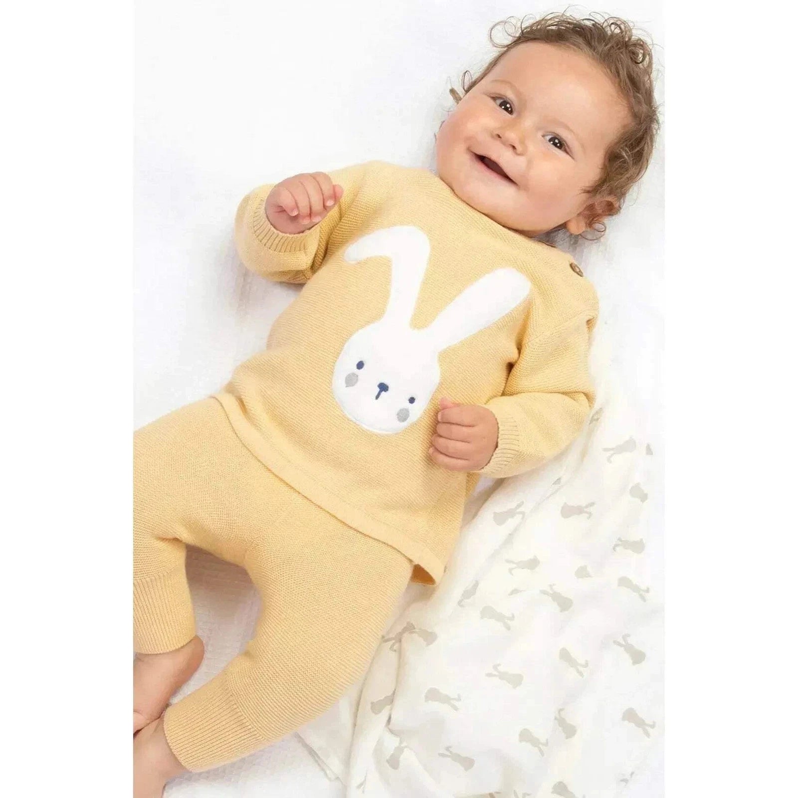 Baby wearing a yellow outfit with a bunny design on a white background